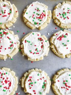 cookies with white frosting and sprinkles on a baking sheet, ready to be baked