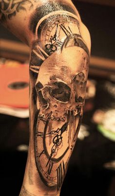 a man's arm with a clock and skull tattoo on it, while he is holding