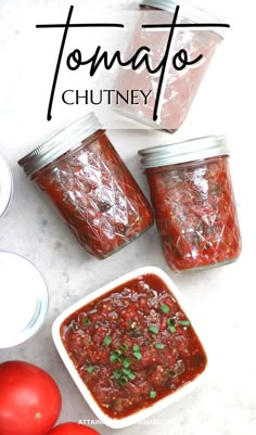 three jars filled with tomato chutney next to tomatoes