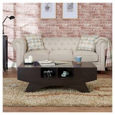 a living room with a couch, coffee table and two pictures on the brick wall