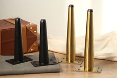 three black and gold poles sitting on top of a wooden floor next to a suitcase