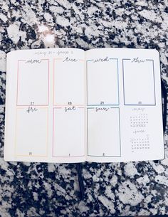 an open planner with notes on it sitting on top of a marble counter next to a pen