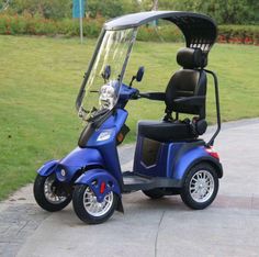 a blue scooter parked on the side of a road next to a park