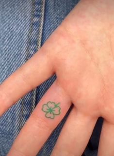 a person's hand with a clover tattoo on it and a green four leaf clover