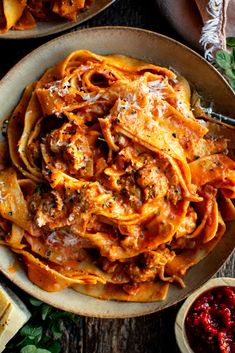 two bowls filled with pasta and sauce on top of a wooden table