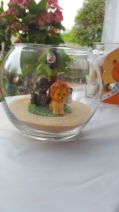 a glass bowl filled with miniature animals on top of a table