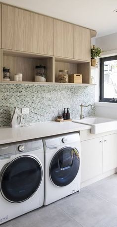 a washer and dryer in a kitchen with cabinets above the washer's counter