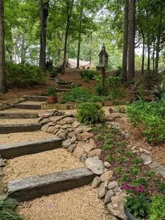 stone steps lead up to the top of a hill in front of trees and flowers