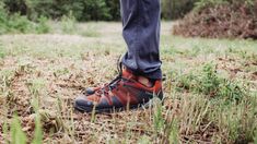 a person standing in the grass wearing hiking shoes