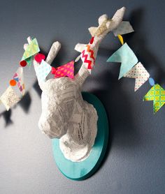 an origami deer head mounted on the wall with paper cranes attached to it