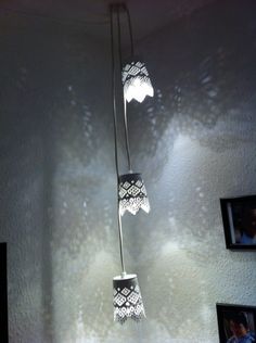 three lights that are hanging from a ceiling in a room with pictures on the wall