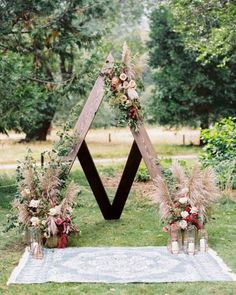 an outdoor ceremony setup with flowers and greenery in vases on the ground, surrounded by trees