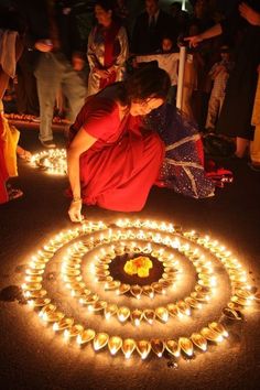 a woman kneeling down in front of a circle of candles with her hands on the ground