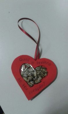 a red heart shaped ornament hanging from a string on a white table top