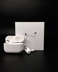 an apple airpods sitting next to its packaging on a black surface with the box open