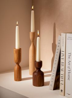 three wooden candlesticks sitting on top of a table next to two bookends