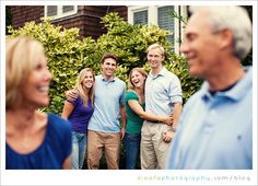 a group of people standing next to each other in front of some bushes and trees