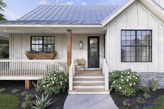 a white house with black shutters and flowers on the front porch, along with steps leading up to the front door