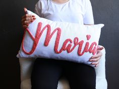 a woman holding a pillow with the word marina on it