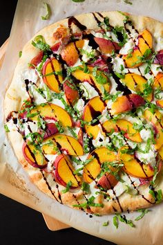 a pizza sitting on top of a cutting board covered in cheese and fruit toppings