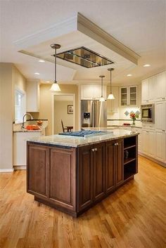 a large kitchen with an island in the middle of it and wooden flooring on both sides