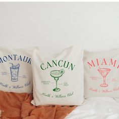 three pillows that have different types of drinks on them, one is white and the other is red