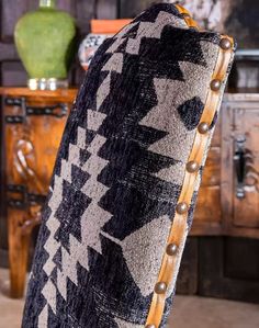 a black and white blanket sitting on top of a wooden table next to a vase