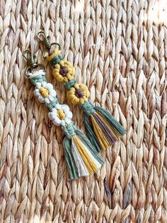 two tassels with yellow and white flowers are on a woven tablecloth,