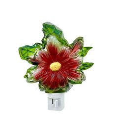 a red and green glass flower on a white wall mounted holder with metal fittings