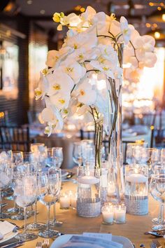 the centerpiece is surrounded by white flowers and candles in glass vases, along with silverware