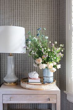 a vase with flowers sitting on top of a table next to a lampshade