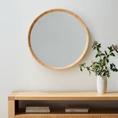 a wooden shelf with a plant and a round mirror on the wall