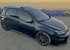 a blue car parked on top of a sandy beach