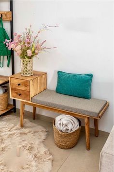 a wooden bench sitting next to a wall with flowers in a vase on top of it