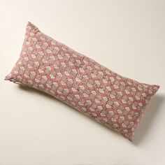 a pink and white pillow sitting on top of a wall next to a wooden frame