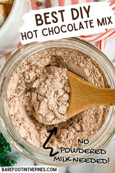 the ingredients for homemade hot chocolate mix in a glass jar with a wooden spoon on top