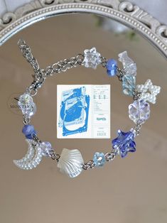 a bracelet with seashells, pearls and other charms on a silver plated mirror