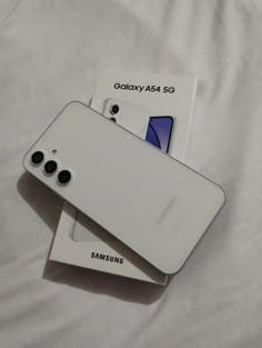 two samsung phones sitting on top of each other next to a package for the phone