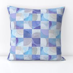 a blue and white checkered pillow with circles on it's side, in front of a white wall