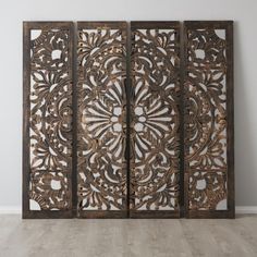 an intricately carved screen in the corner of a room with hardwood floors and white walls