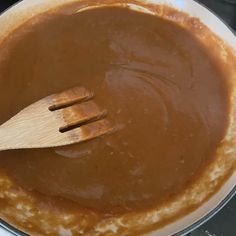 a wooden spatula in a pan filled with brown sauce on top of a stove