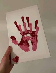 someone is holding up a handprint with red paint on it