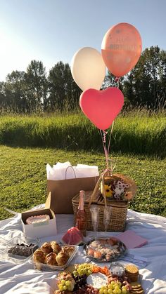 a table topped with lots of food and balloons in the shape of heart shaped balloons