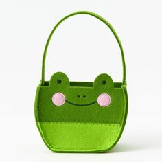 a green purse with a smiling frog on it's front and pink eyes in the center