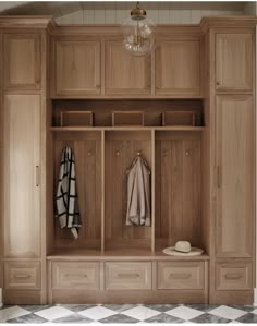 a wooden coat rack with two coats hanging on it's sides and three drawers