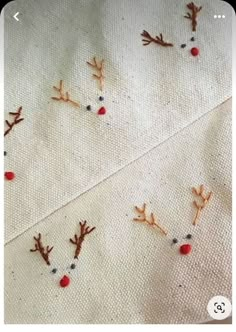 embroidered reindeers on white fabric with red noses and nose holes in the middle, viewed from above