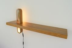 a wooden shelf with a light on it and a cord hanging from the wall next to it