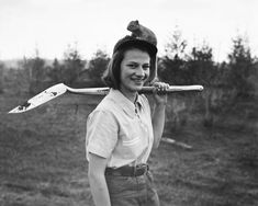 a black and white photo of a woman holding a baseball bat with a mouse on top of her head