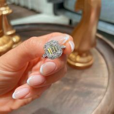 a woman's hand holding a ring with a yellow and white diamond in it