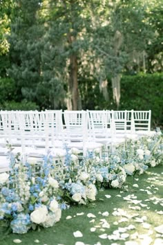 rows of white chairs with blue and white flowers on the grass in front of them